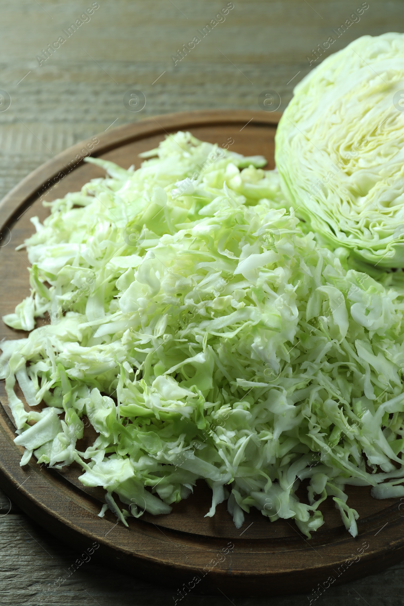 Photo of Fresh shredded cabbage on wooden table, closeup