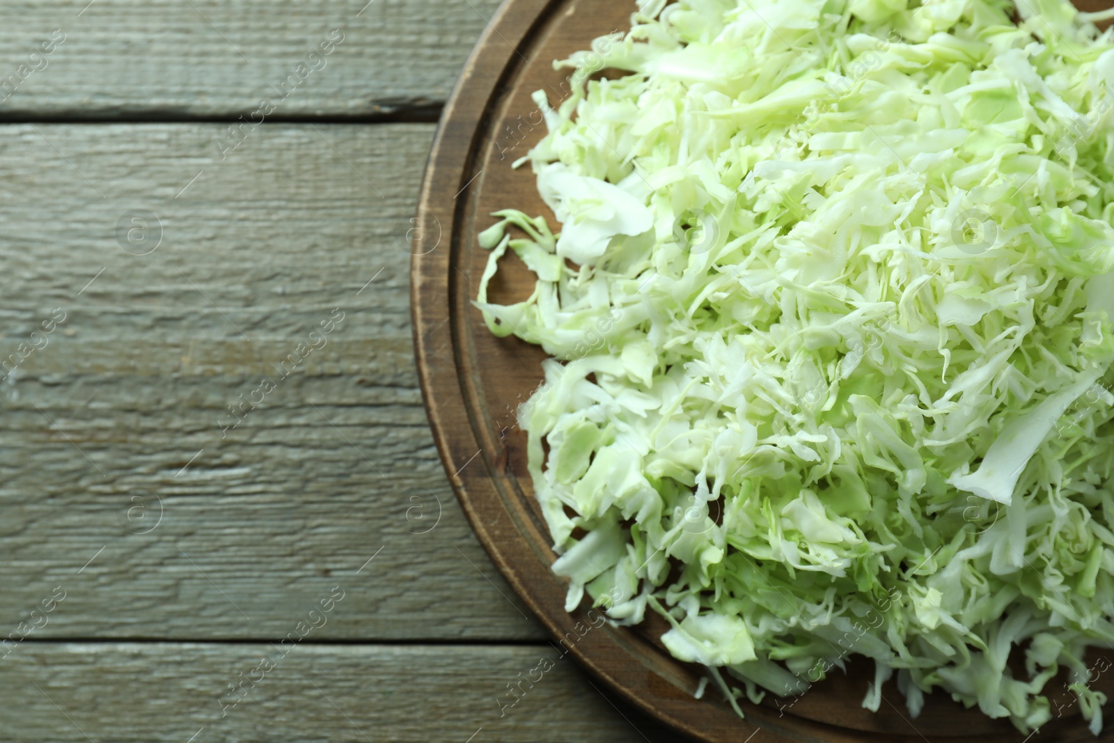 Photo of Fresh shredded cabbage on wooden table, top view. Space for text