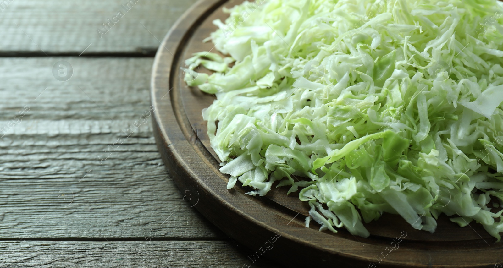 Photo of Fresh shredded cabbage on wooden table, closeup