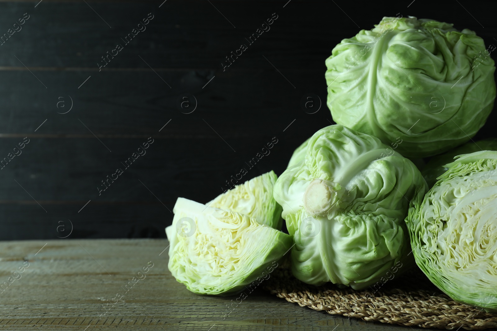 Photo of Whole and cut fresh cabbages on wooden table. Space for text