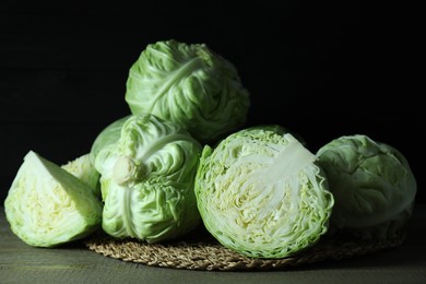 Whole and cut fresh cabbages on wooden table