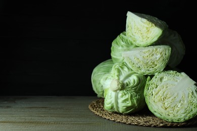 Photo of Whole and cut fresh cabbages on wooden table. Space for text