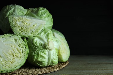 Photo of Whole and cut fresh cabbages on wooden table. Space for text