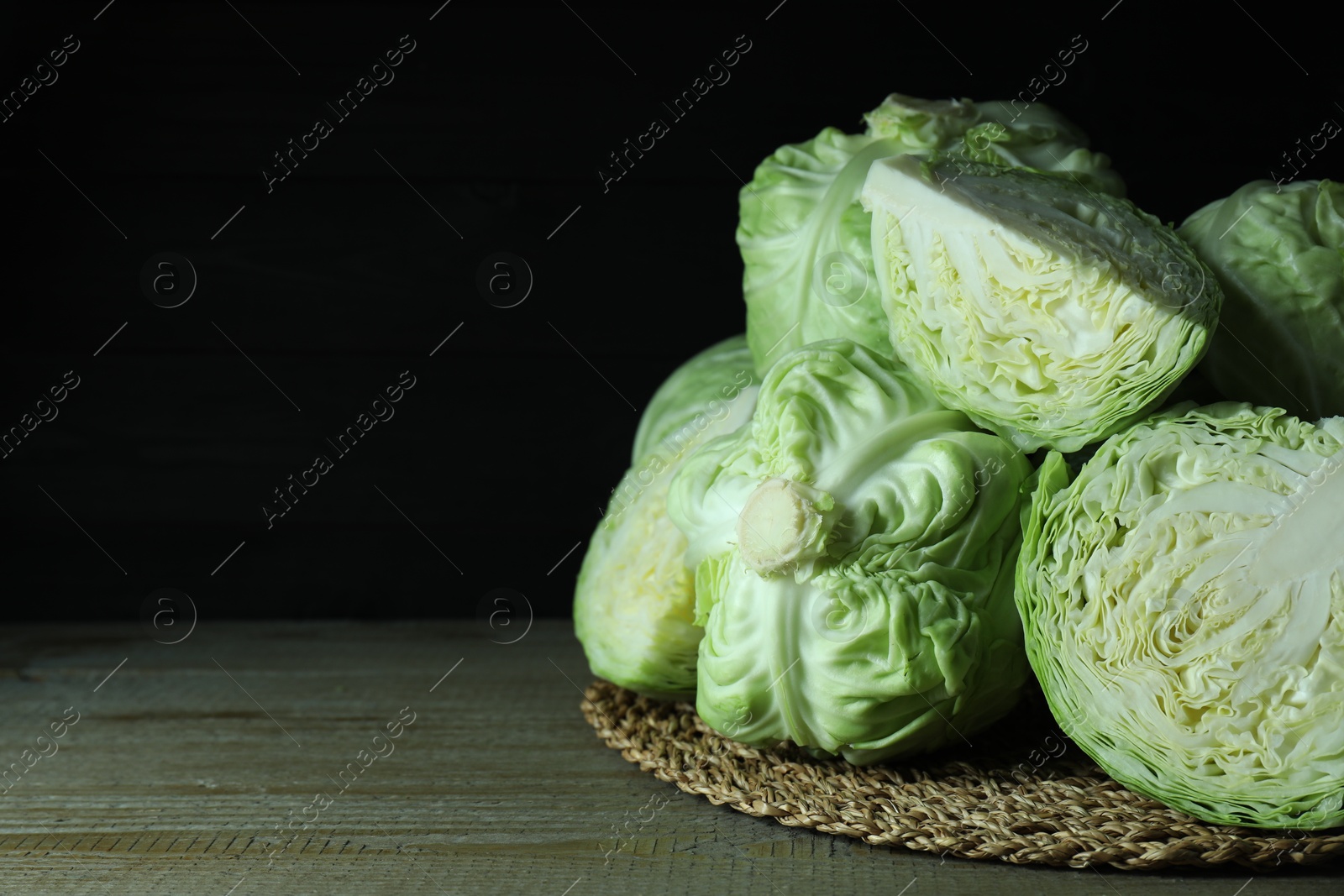 Photo of Whole and cut fresh cabbages on wooden table. Space for text