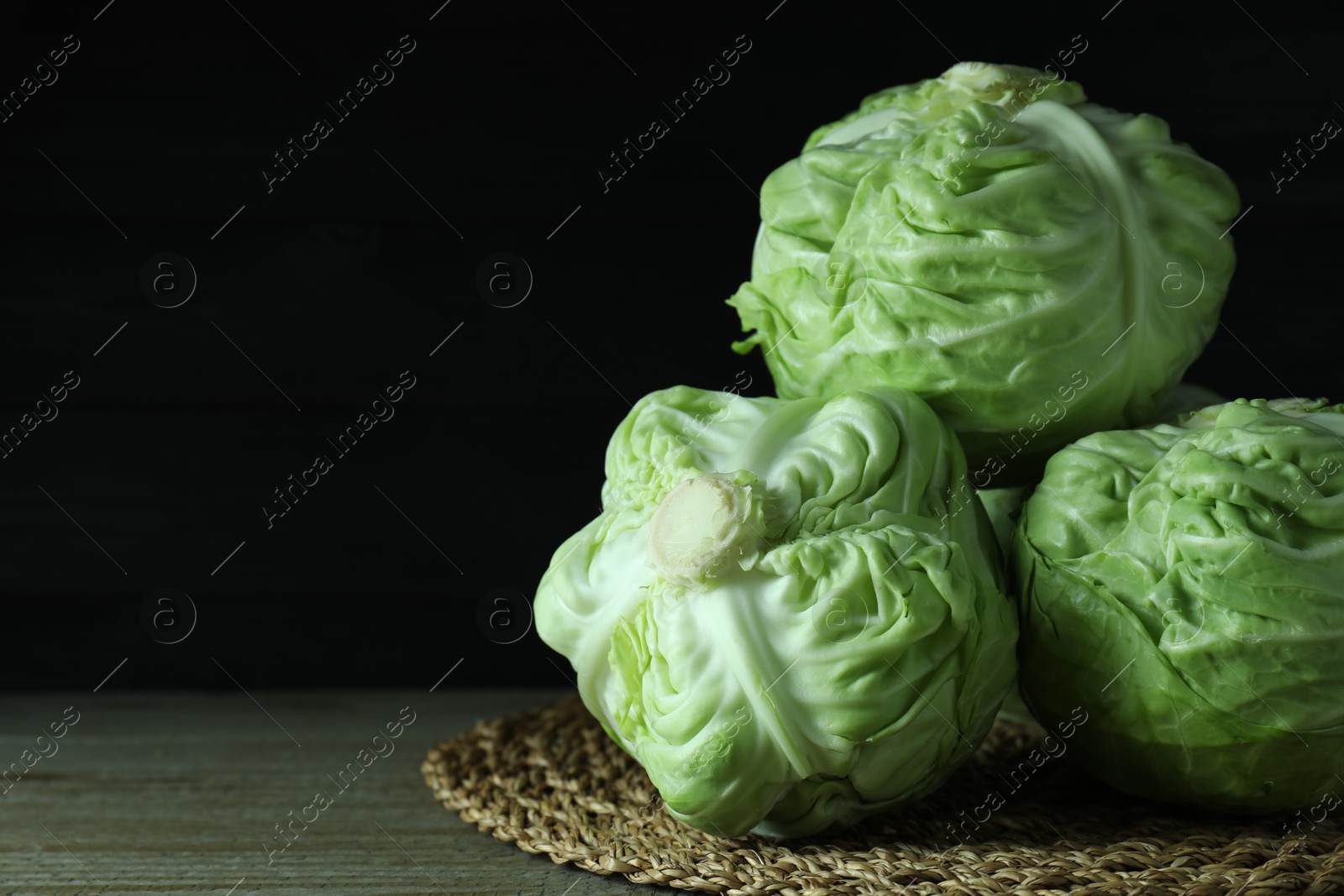 Photo of Three heads of cabbage on wooden table, closeup. Space for text