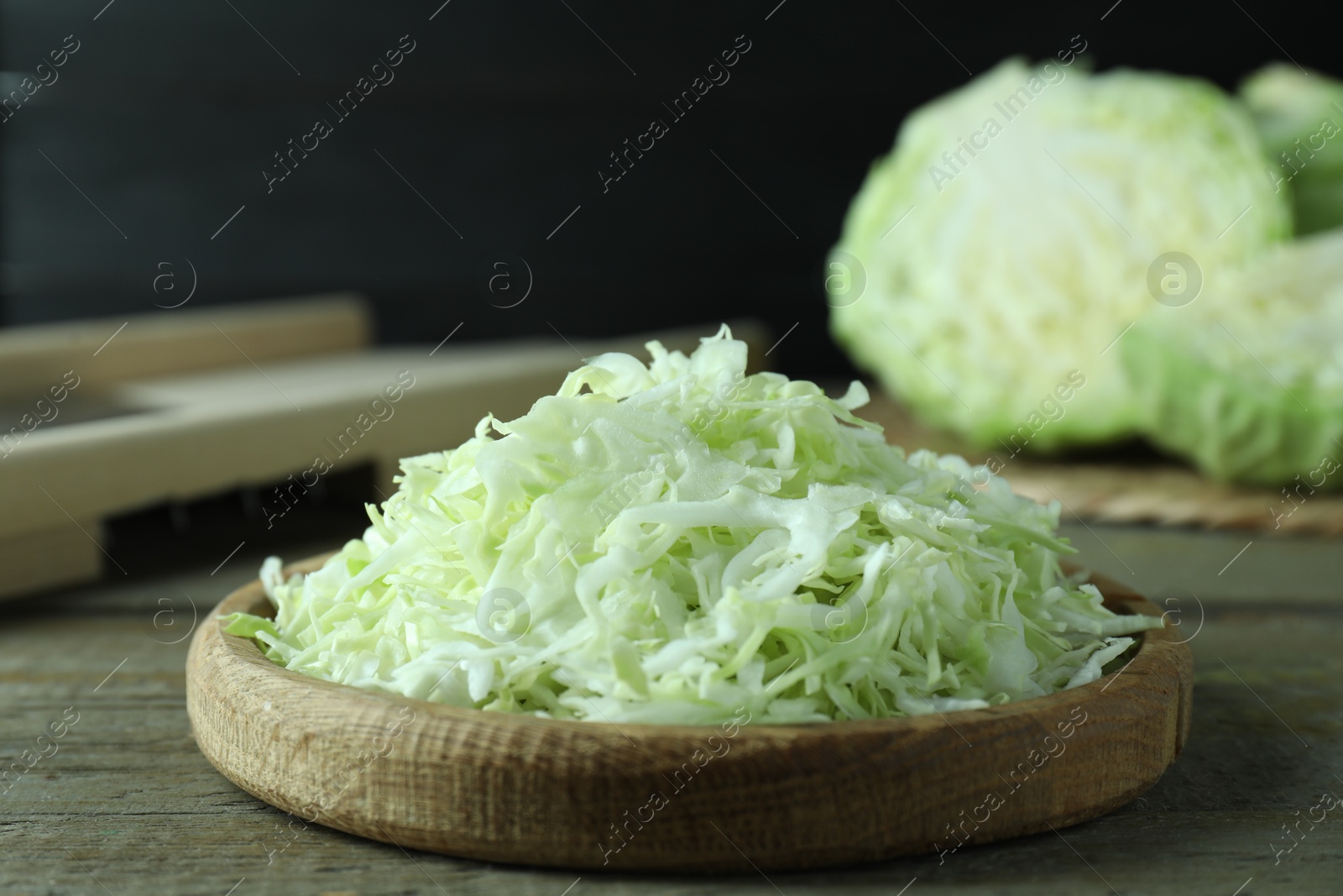 Photo of Fresh shredded cabbage on wooden table, closeup