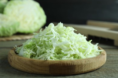 Photo of Fresh shredded cabbage on wooden table, closeup