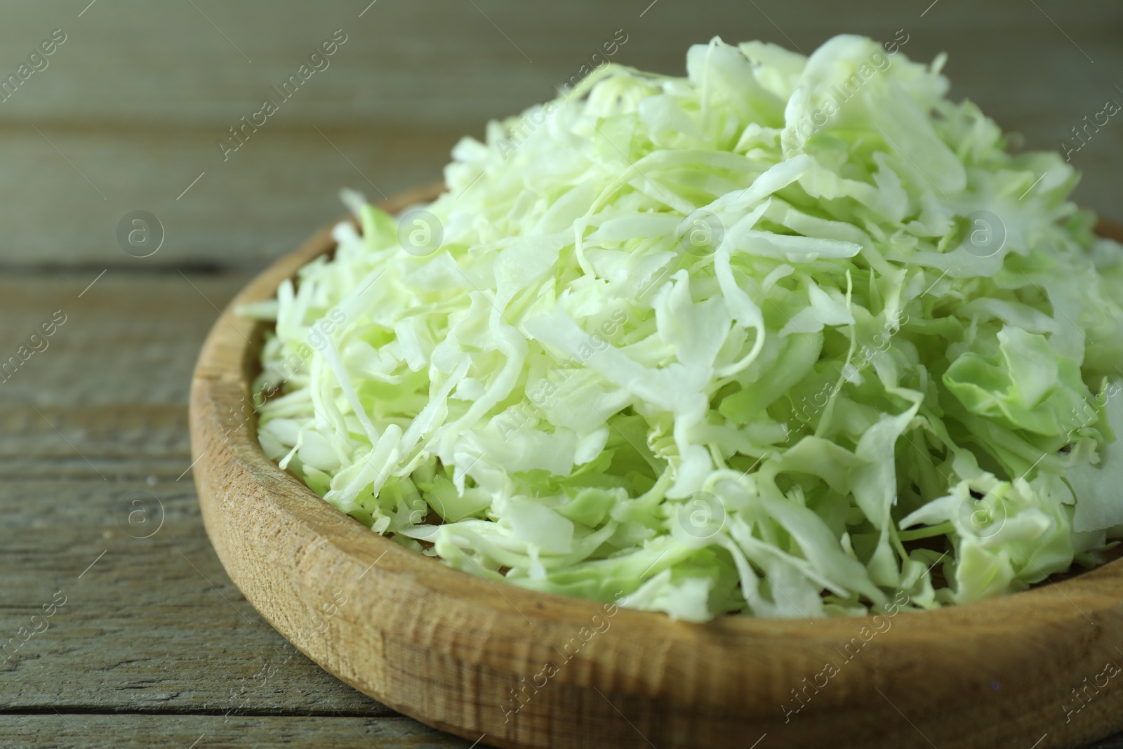 Photo of Fresh shredded cabbage on wooden table, closeup