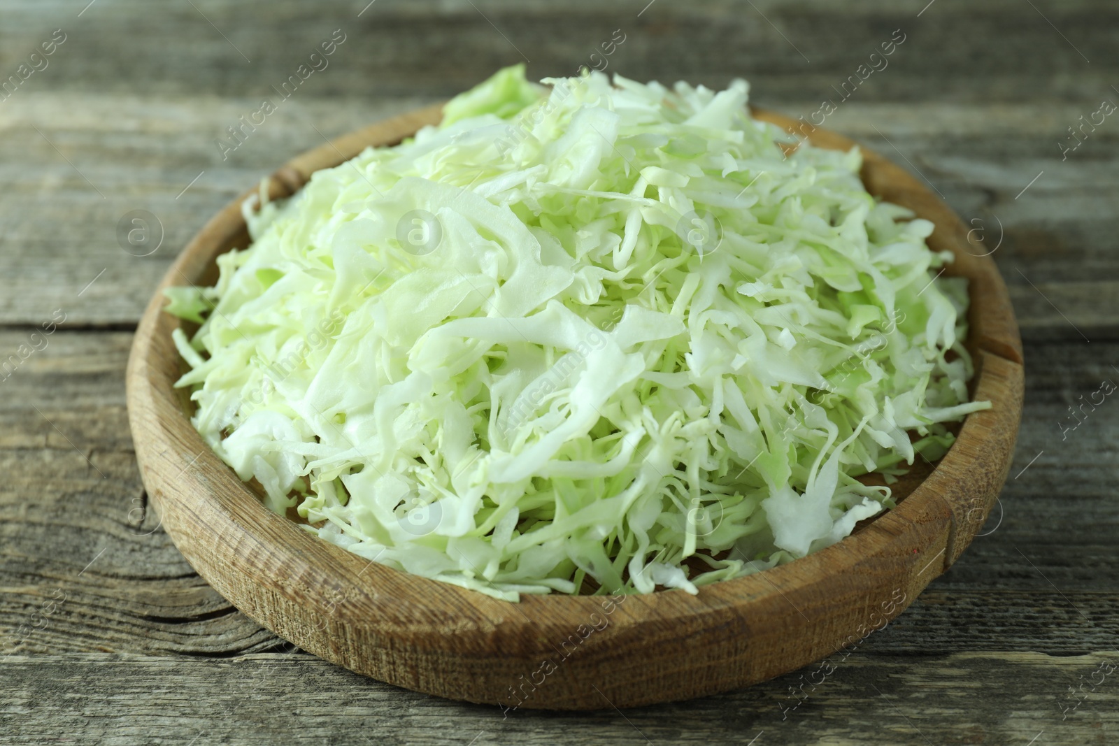 Photo of Fresh shredded cabbage on wooden table, closeup