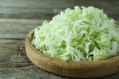 Photo of Fresh shredded cabbage on wooden table, closeup