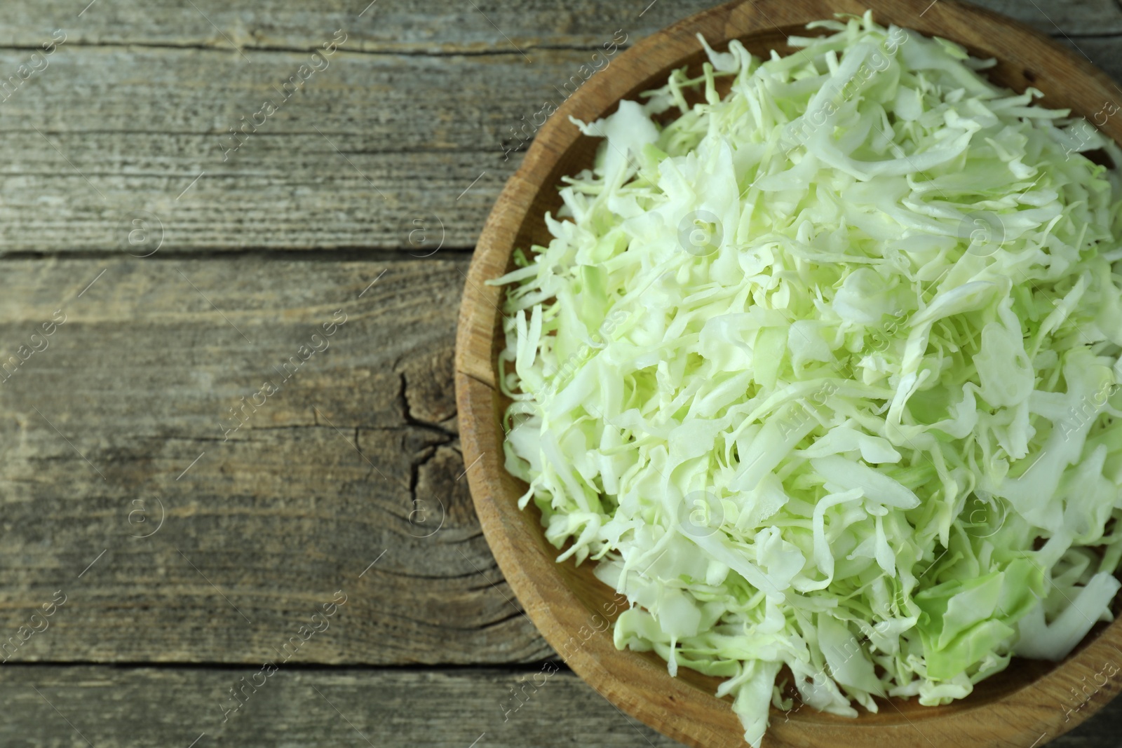 Photo of Fresh shredded cabbage on wooden table, top view. Space for text