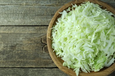 Photo of Fresh shredded cabbage on wooden table, top view. Space for text