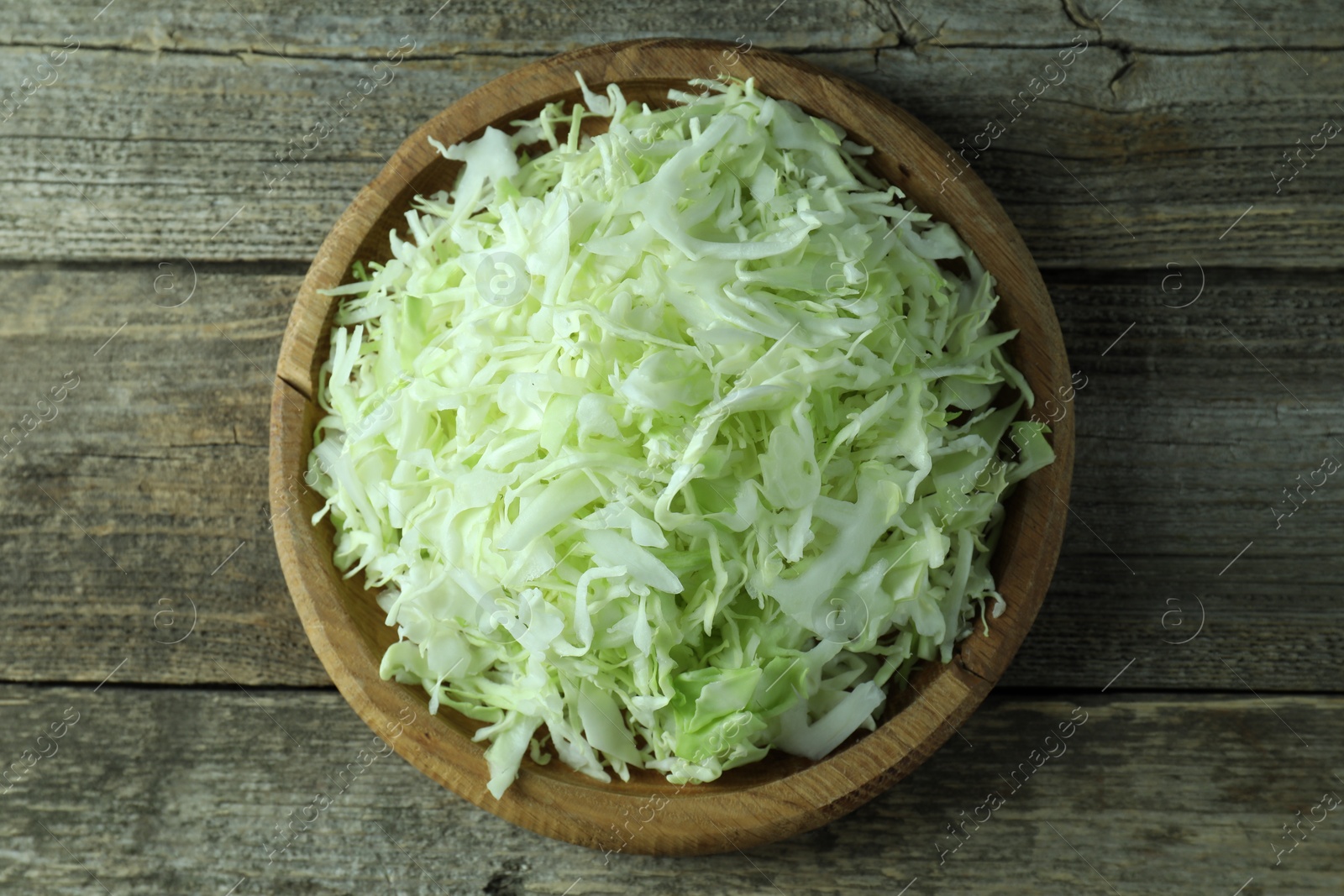 Photo of Fresh shredded cabbage on wooden table, top view