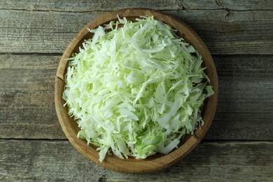 Photo of Fresh shredded cabbage on wooden table, top view