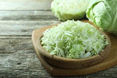 Photo of Fresh shredded cabbage on wooden table, closeup