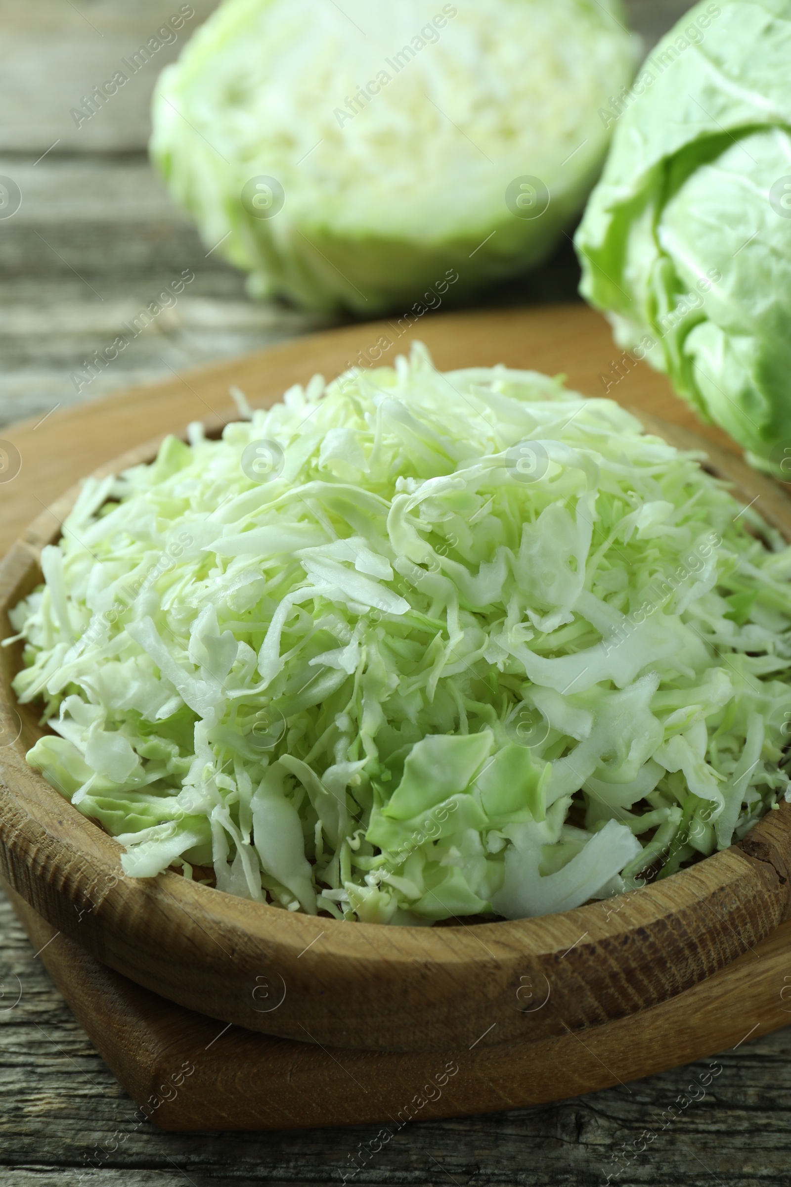 Photo of Fresh shredded cabbage on wooden table, closeup