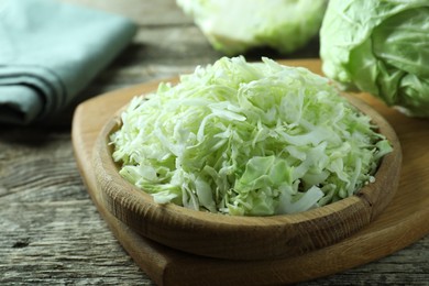 Photo of Fresh shredded cabbage on wooden table, closeup