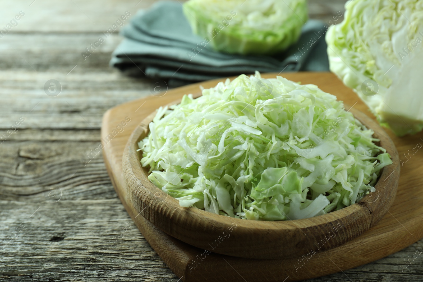 Photo of Fresh shredded cabbage on wooden table, closeup