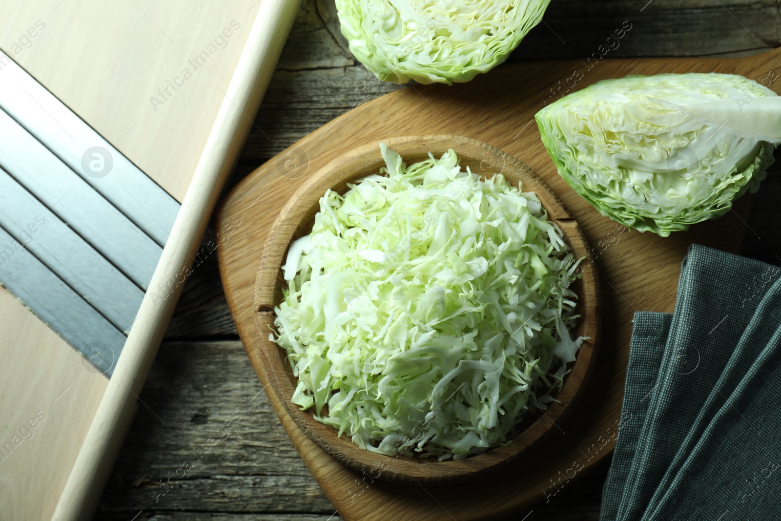 Photo of Fresh shredded cabbage and shredder on wooden table, flat lay