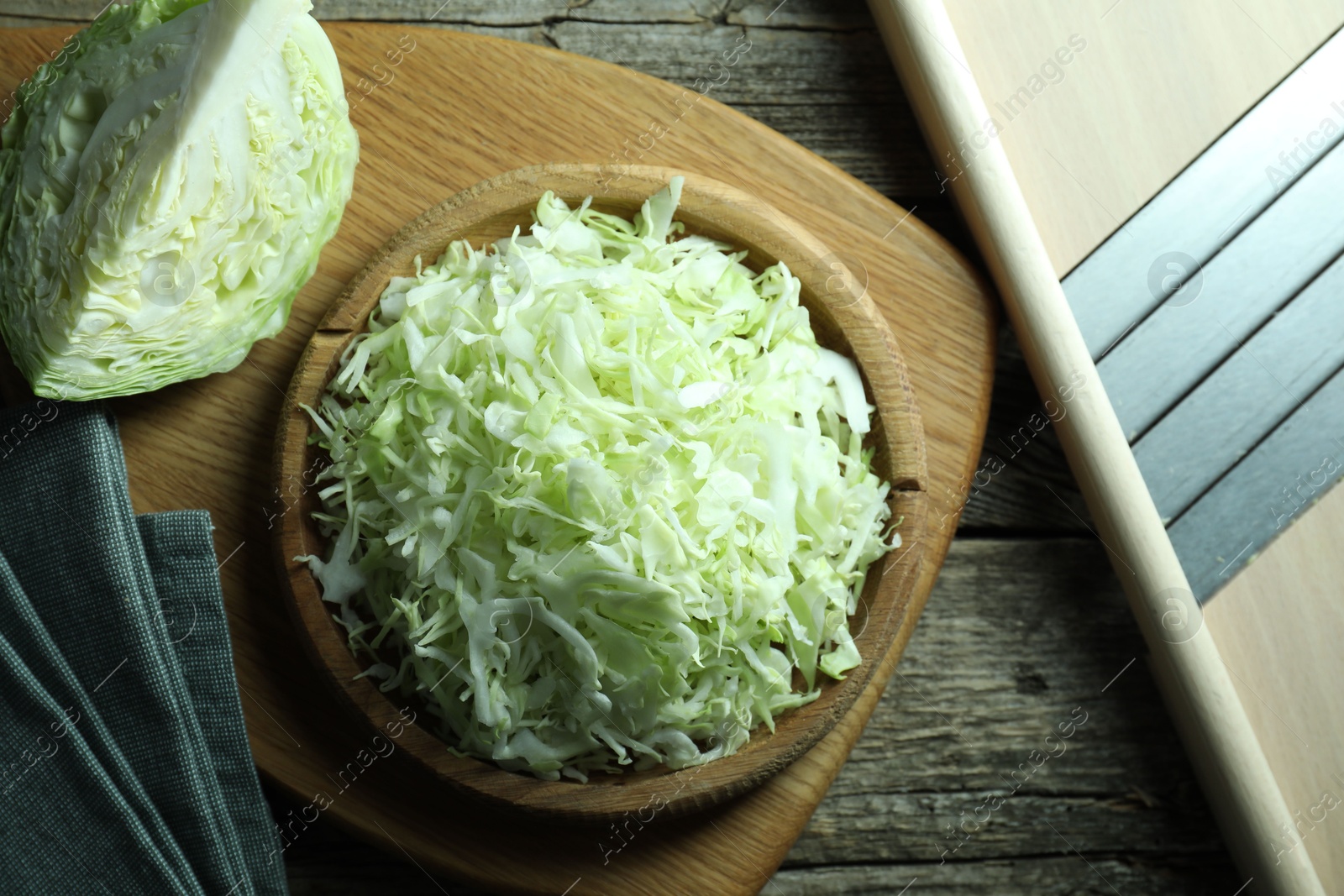 Photo of Fresh shredded cabbage and shredder on wooden table, flat lay