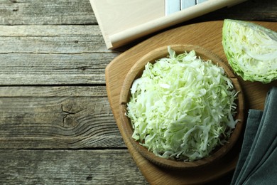 Photo of Fresh shredded cabbage and shredder on wooden table, flat lay. Space for text