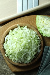 Photo of Fresh shredded cabbage and shredder on wooden table, flat lay