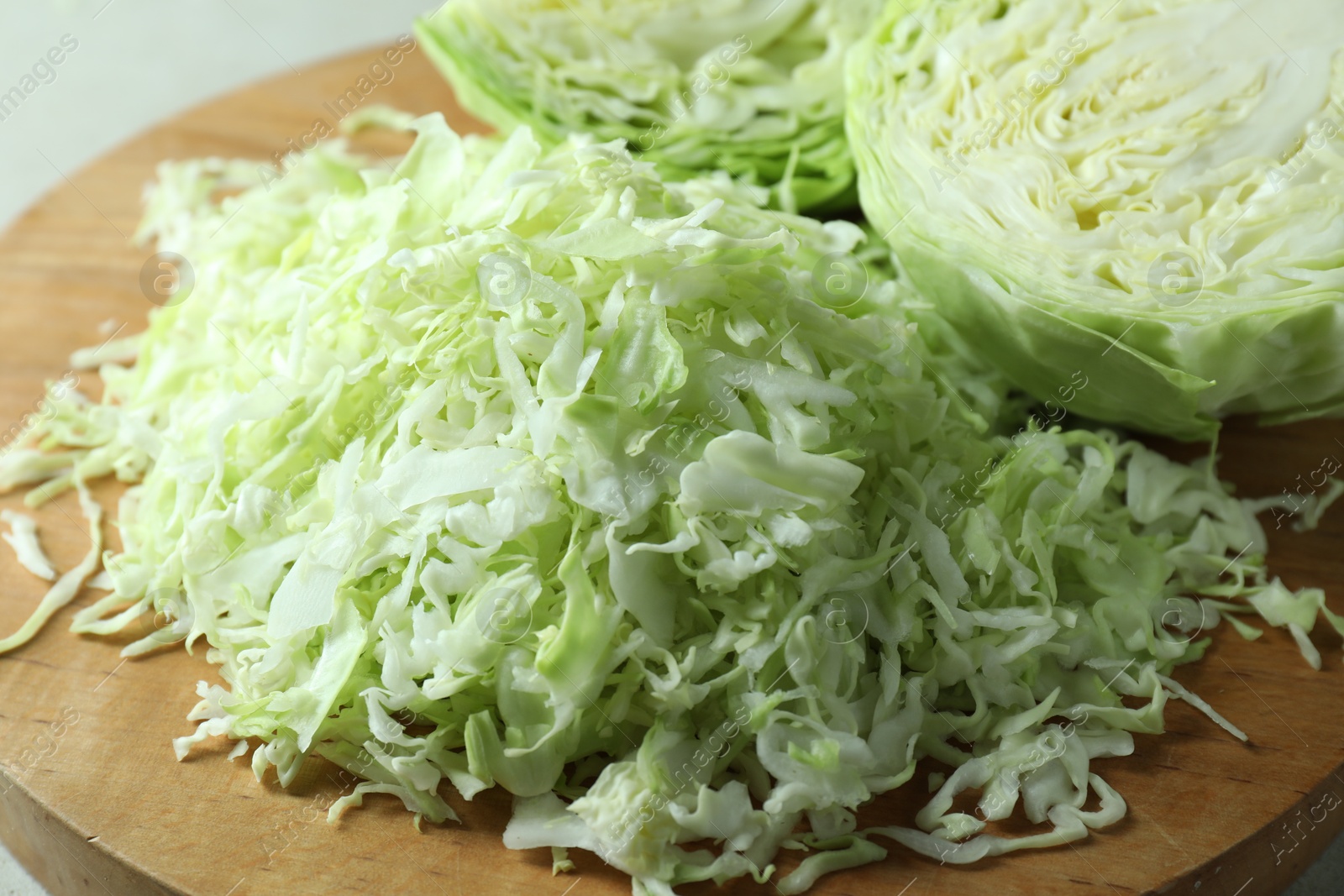 Photo of Fresh shredded cabbage on wooden board, closeup