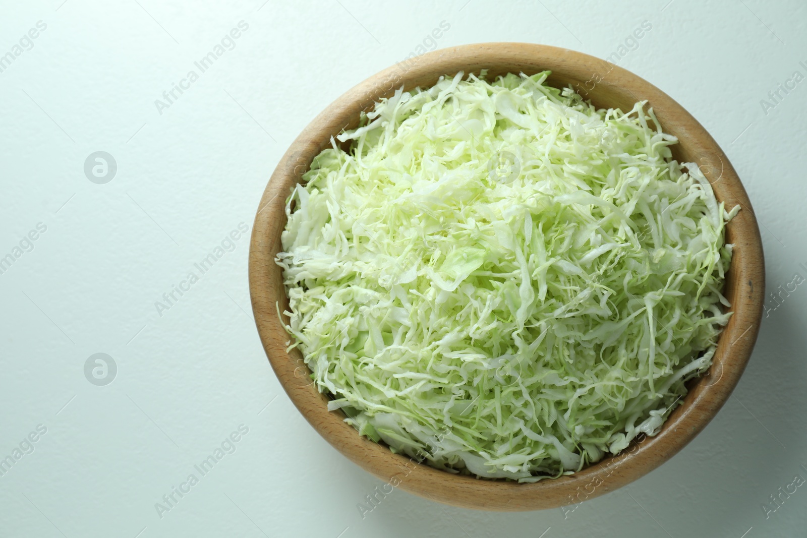 Photo of Fresh shredded cabbage on light table, top view. Space for text