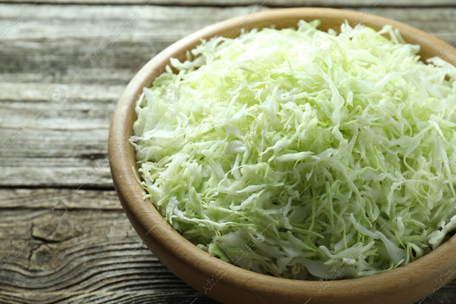 Photo of Fresh shredded cabbage on wooden table, closeup