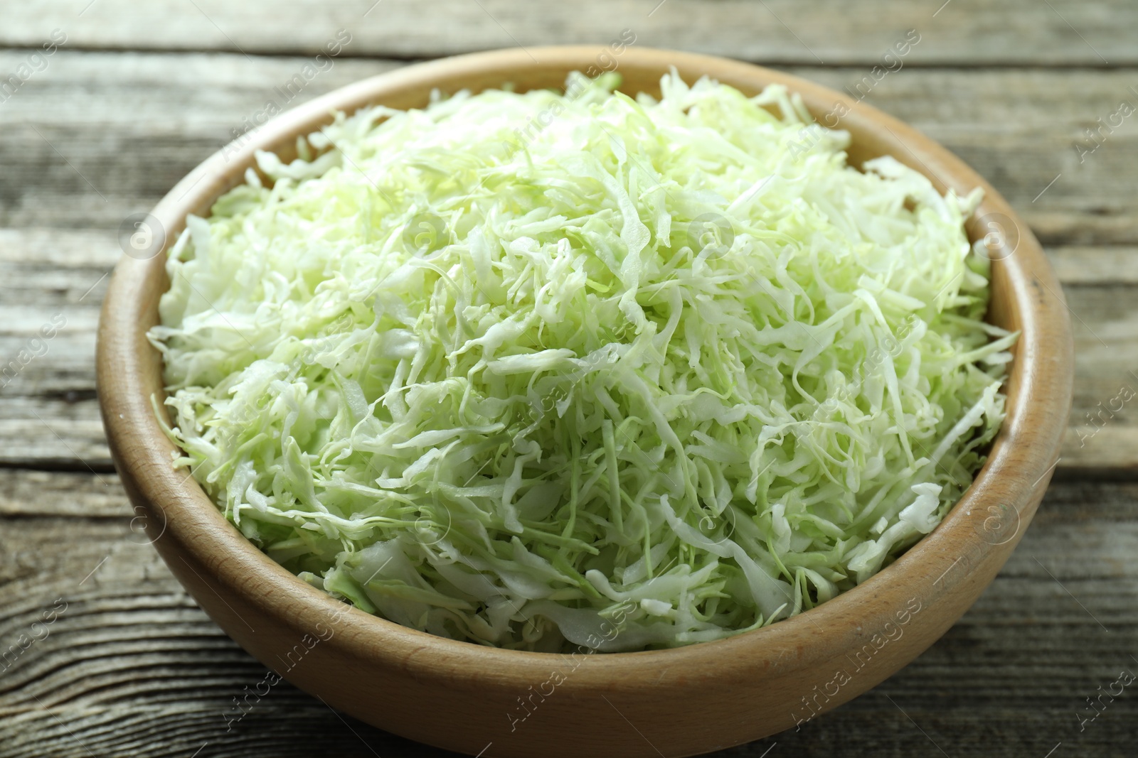 Photo of Fresh shredded cabbage on wooden table, closeup