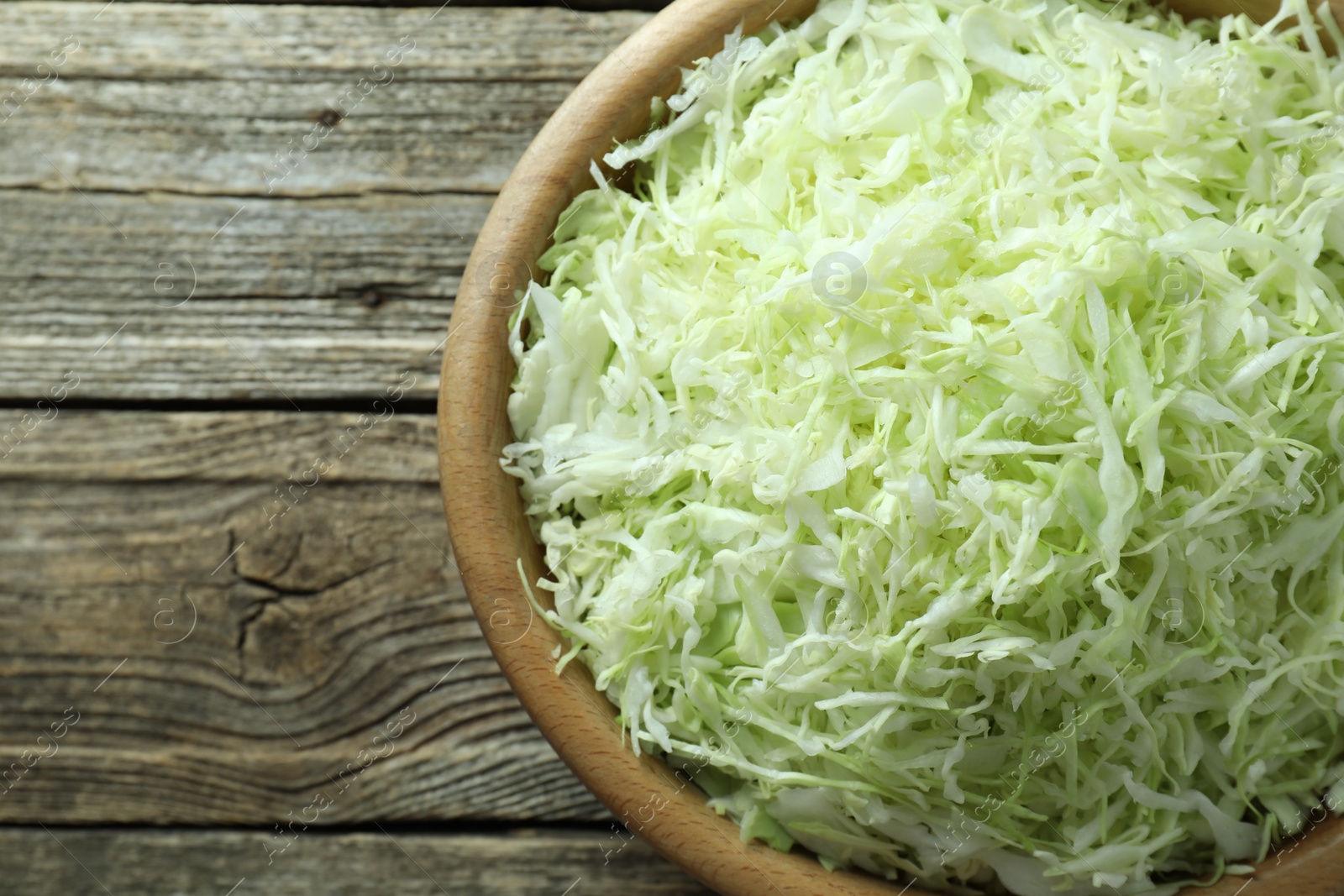 Photo of Fresh shredded cabbage on wooden table, top view. Space for text