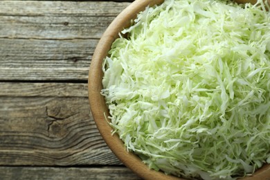 Photo of Fresh shredded cabbage on wooden table, top view. Space for text