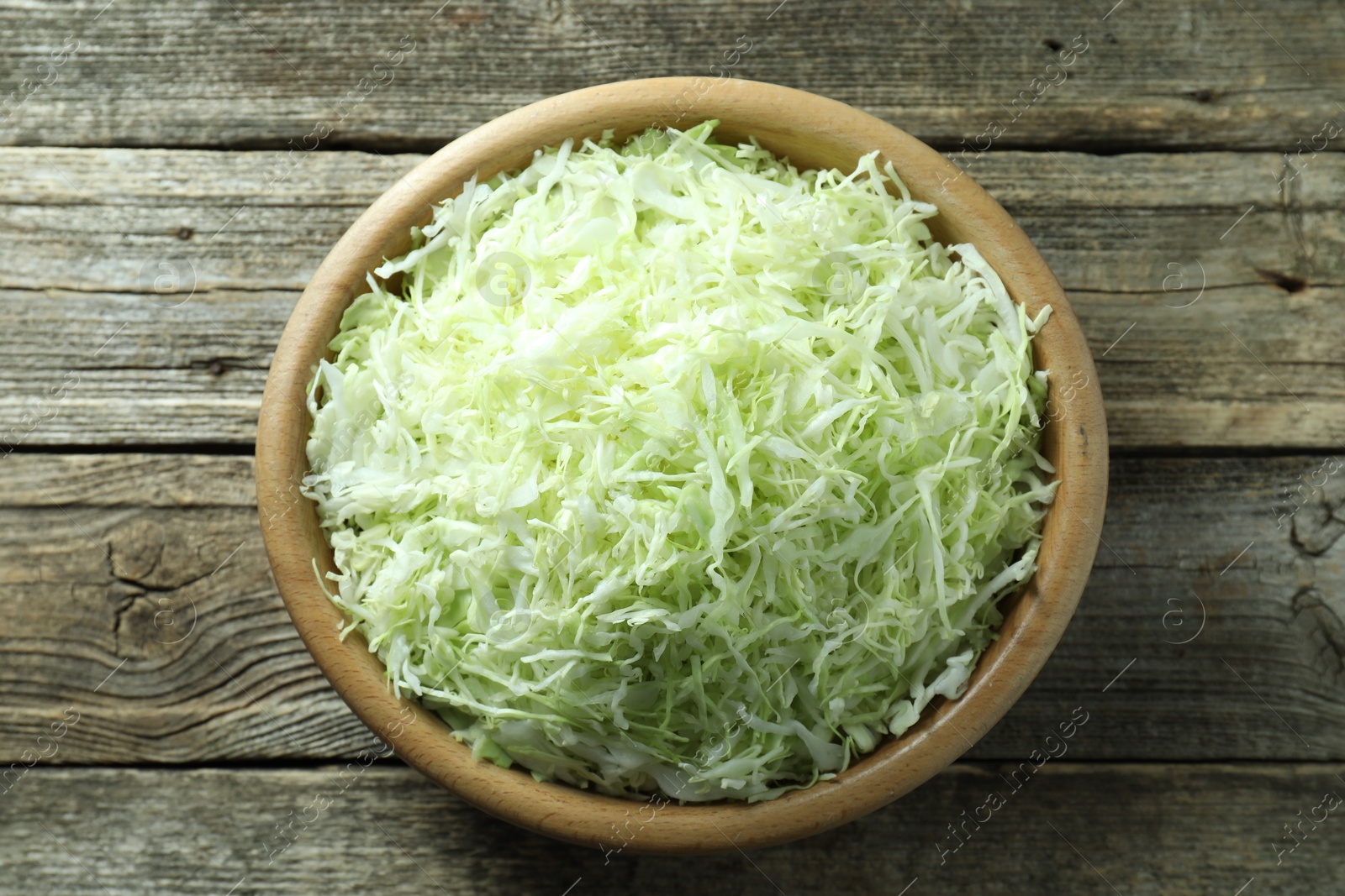 Photo of Fresh shredded cabbage on wooden table, top view