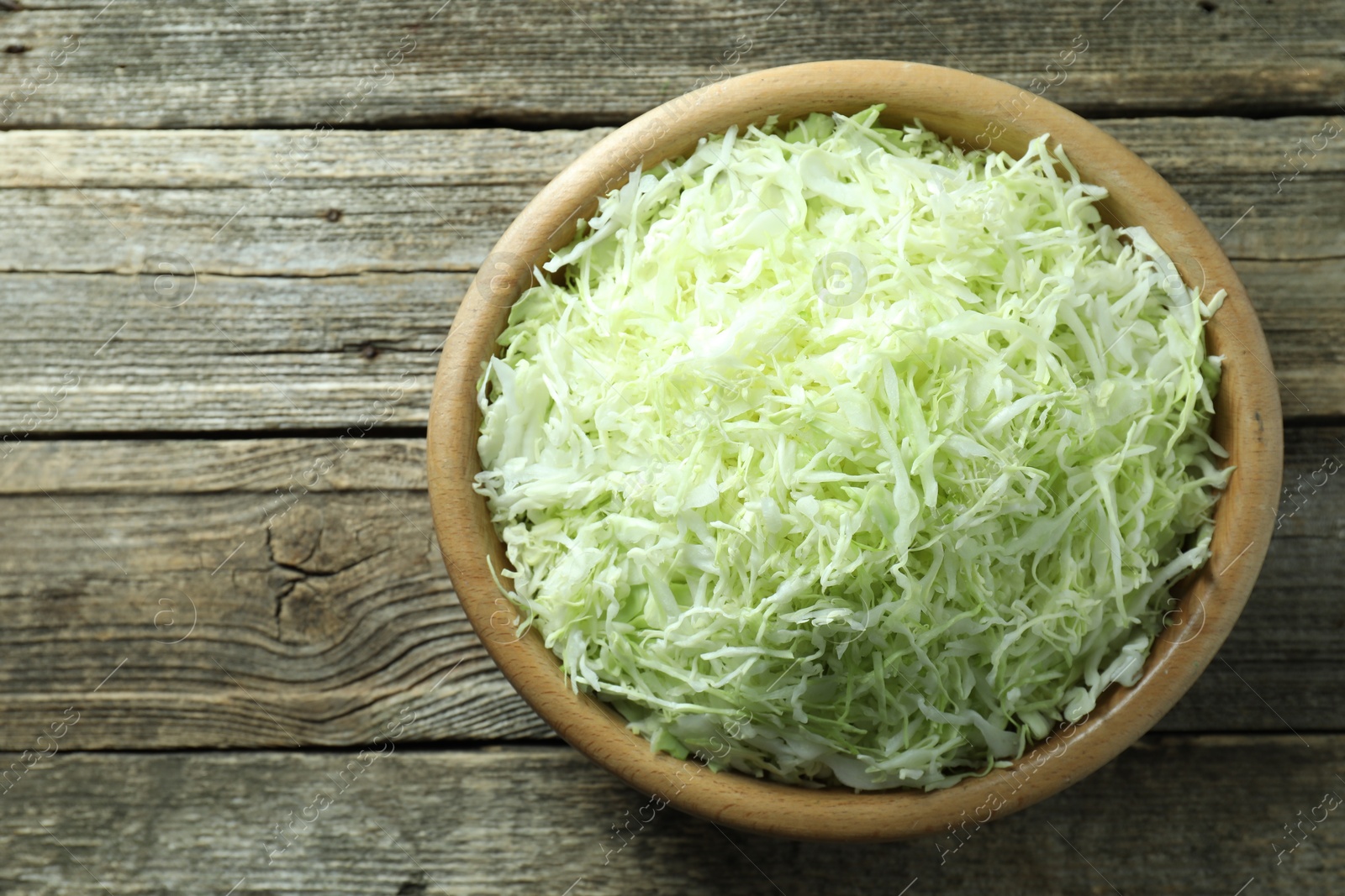 Photo of Fresh shredded cabbage on wooden table, top view. Space for text