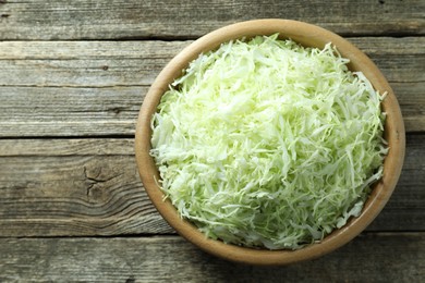 Photo of Fresh shredded cabbage on wooden table, top view. Space for text