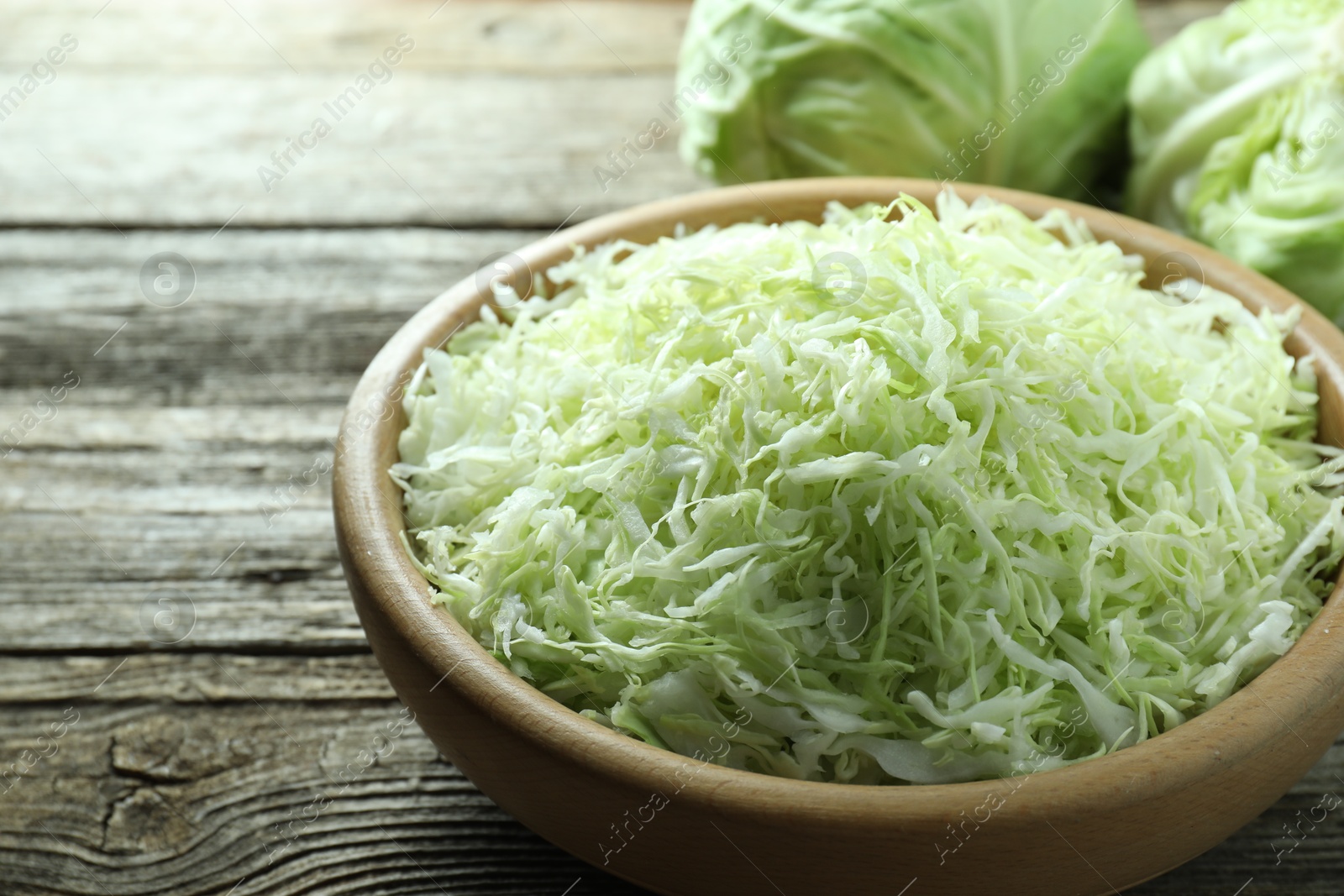 Photo of Fresh shredded cabbage on wooden table, closeup