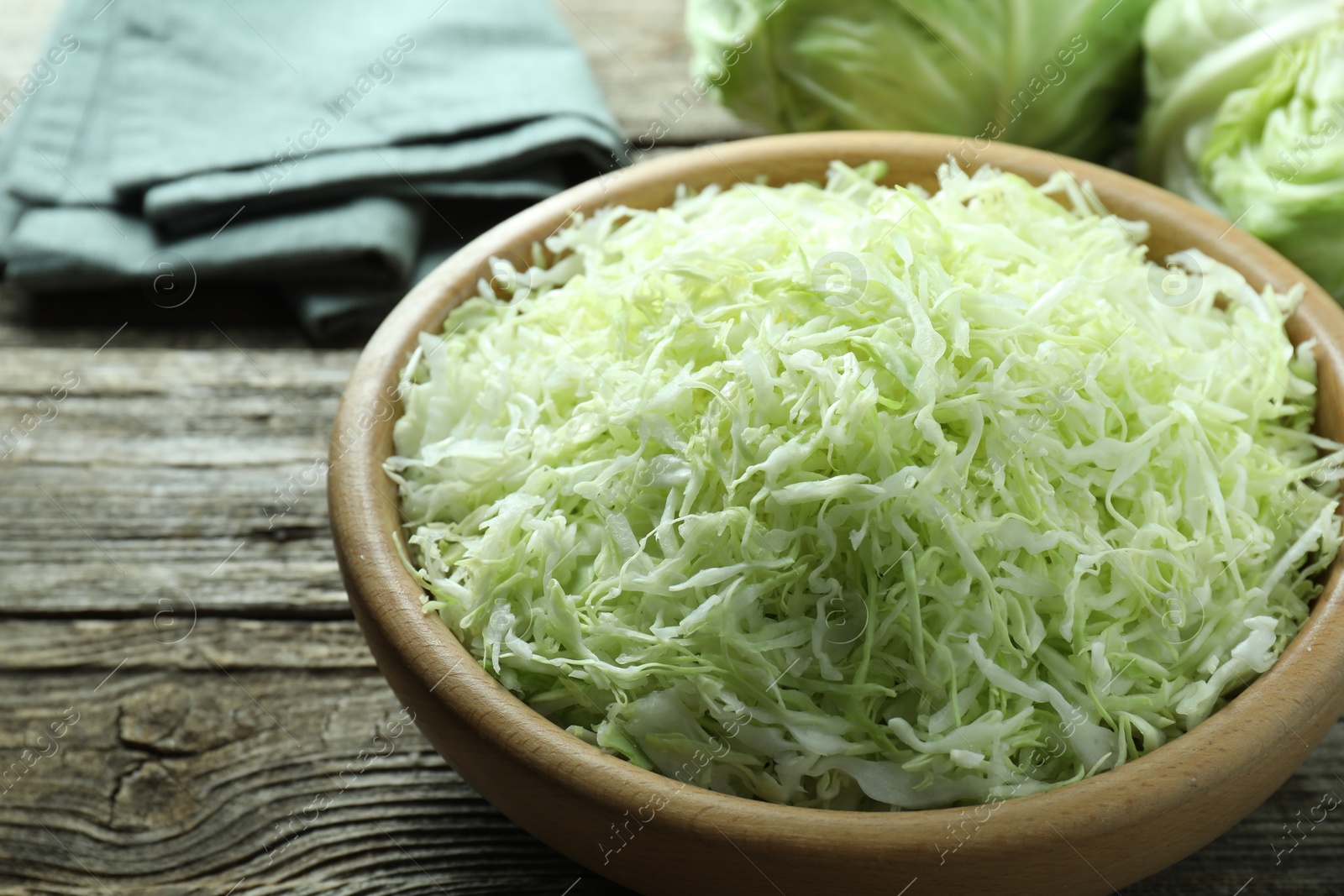 Photo of Fresh shredded cabbage on wooden table, closeup