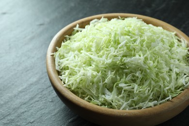 Photo of Fresh shredded cabbage on black table, closeup