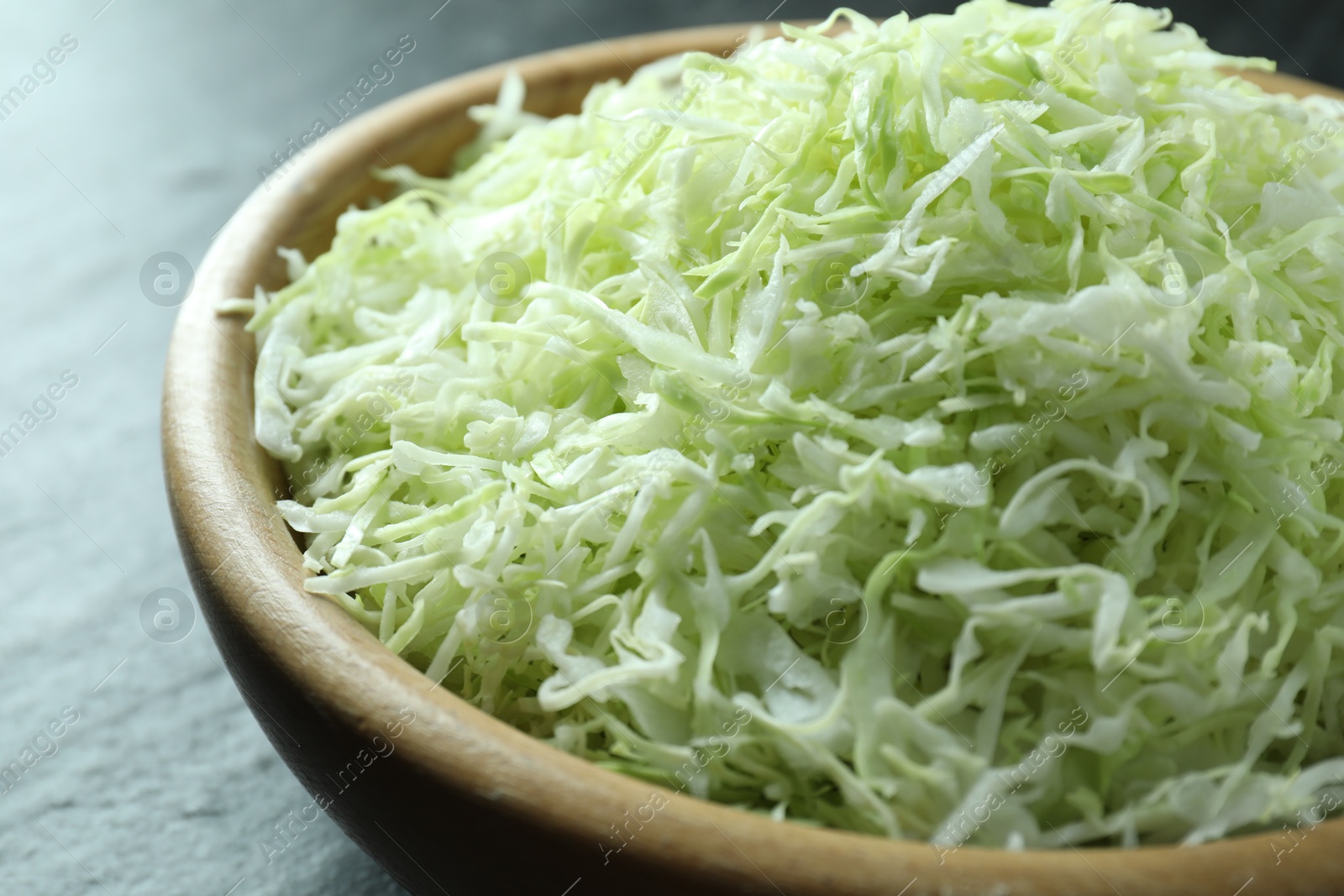 Photo of Fresh shredded cabbage on black table, closeup