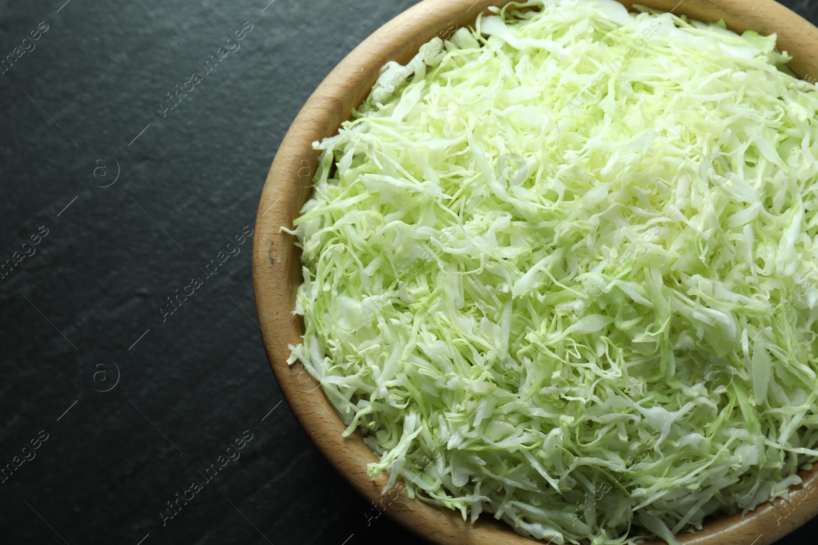 Photo of Fresh shredded cabbage on black table, top view