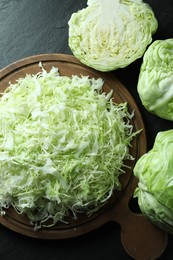 Fresh shredded cabbage on black table, flat lay