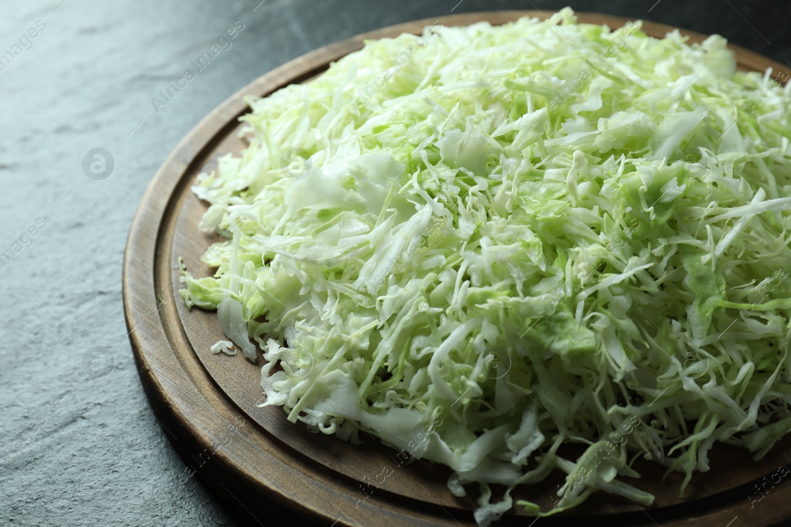 Photo of Fresh shredded cabbage on black table, closeup