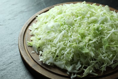 Photo of Fresh shredded cabbage on black table, closeup