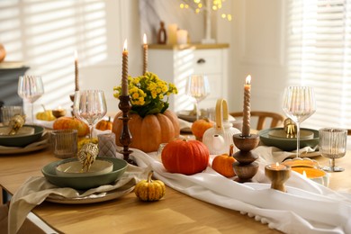 Photo of Stylish table setting with beautiful dishware, glasses and autumn decor in dining room