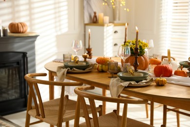 Stylish table setting with beautiful dishware, glasses and autumn decor in dining room