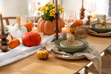 Stylish table setting with beautiful dishware, glasses and autumn decor in dining room