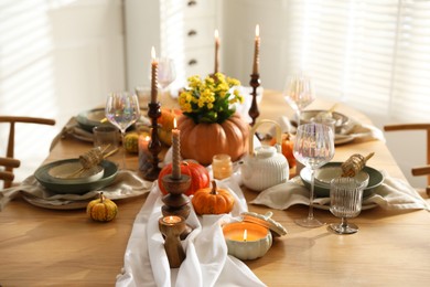 Stylish table setting with beautiful dishware, glasses and autumn decor in dining room