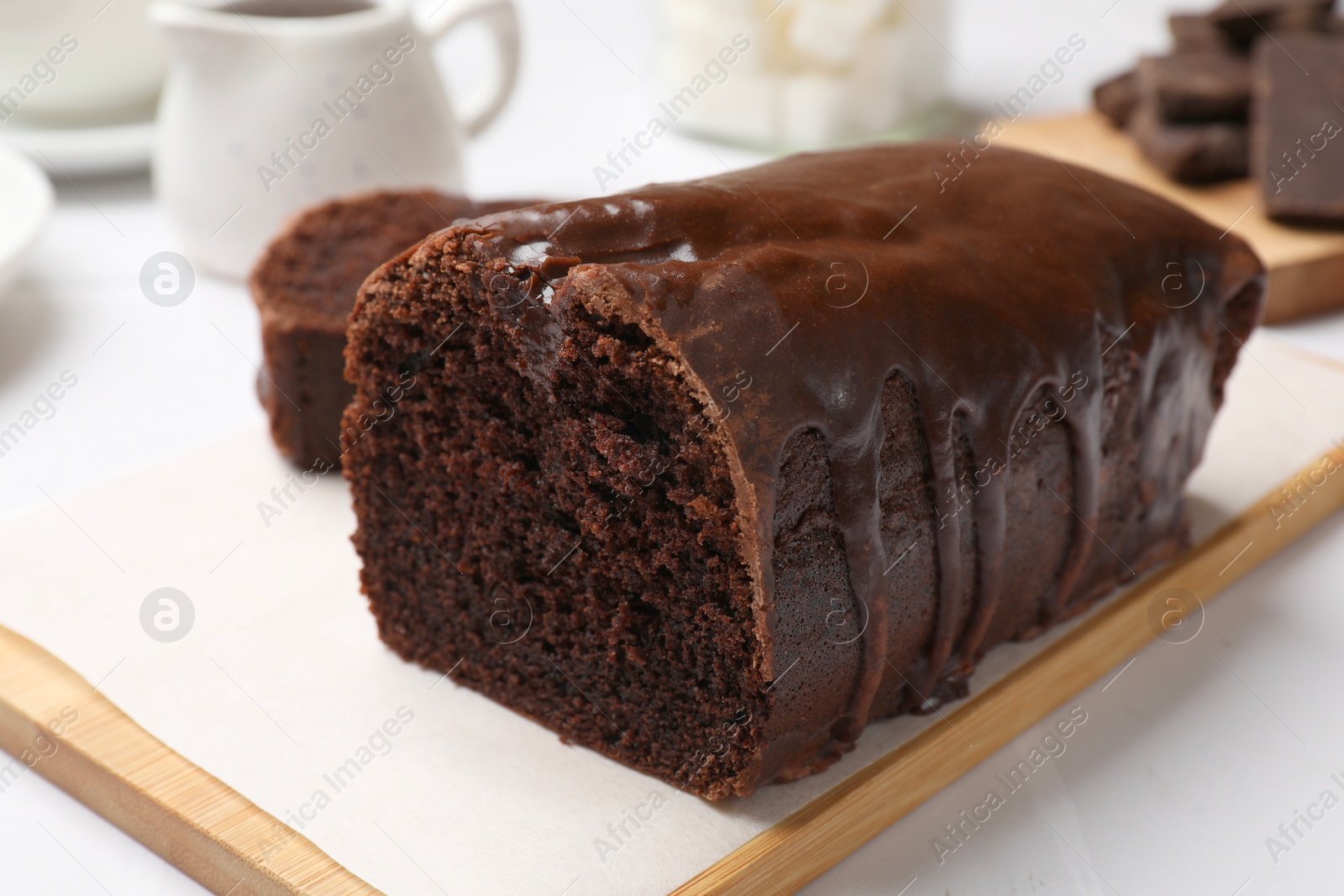 Photo of Delicious chocolate sponge cake on white tiled table, closeup