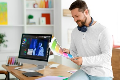 Smiling designer with color palette in office