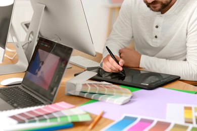 Designer working with tablet at table in office, closeup